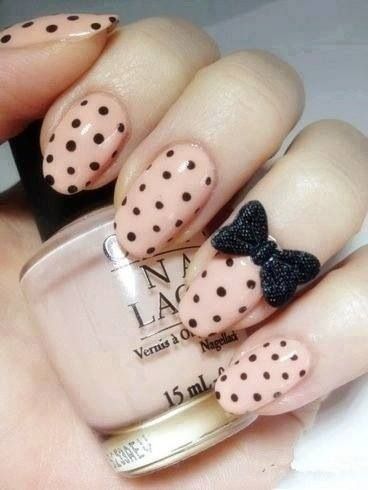 Black dots on nails with nude shade and a bow embellishment looks so elegant