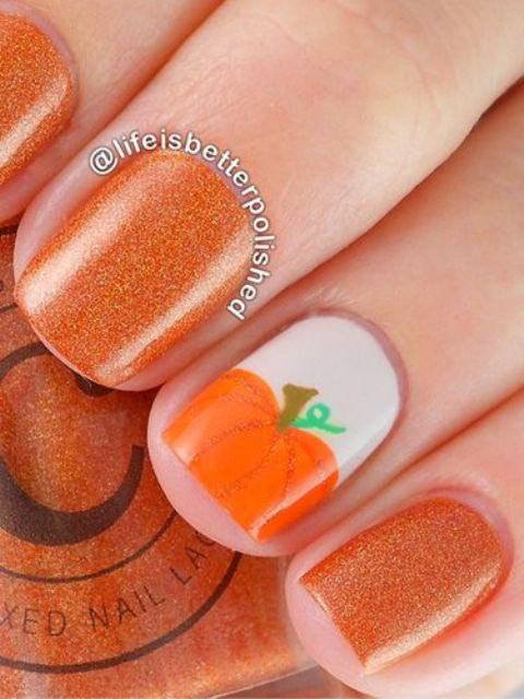 Glitter orange nails with a pumpkin accent