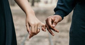Man and woman holding pinky fingers together