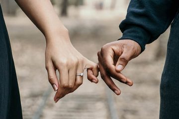 Man and woman holding pinky fingers together