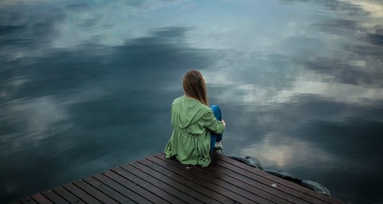 Solitary woman with PTSD, sitting in contemplation.