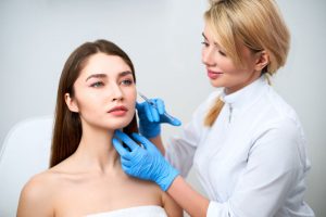 Doctor performing dermal filler injection procedure on a patient's face.