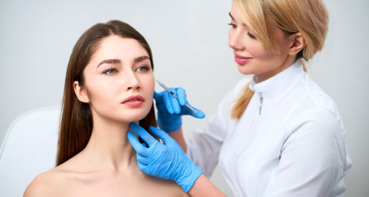 Doctor performing dermal filler injection procedure on a patient's face.