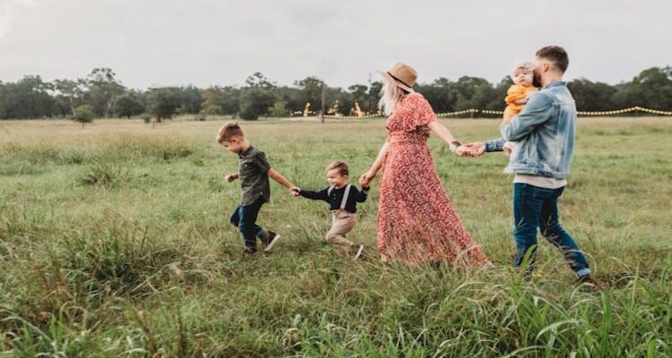 Happy family of five walking through the field.