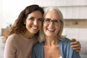 Two women smiling confidently after receiving dental prostheses.