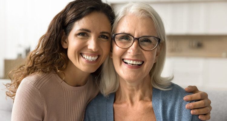 Two women smiling confidently after receiving dental prostheses.