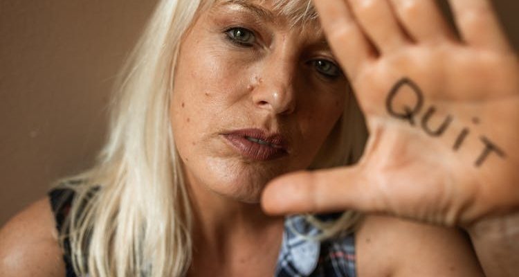 A woman's hand with 'Quit' written on it, symbolizing her determination to overcome addiction.