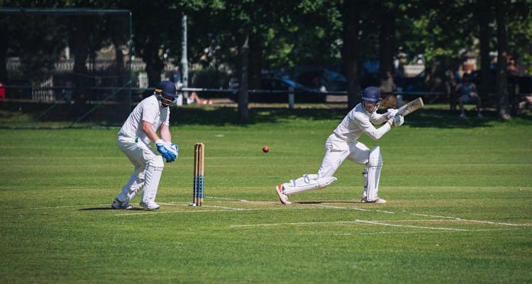 A cricketer swings his bat, focused and determined, in the heart of the game.