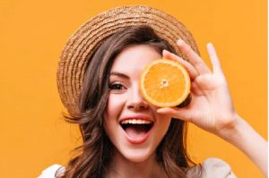 A girl holding an orange, symbolizing the benefits of Vitamin C for radiant skin.
