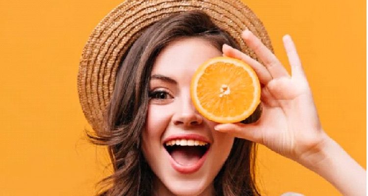 A girl holding an orange, symbolizing the benefits of Vitamin C for radiant skin.