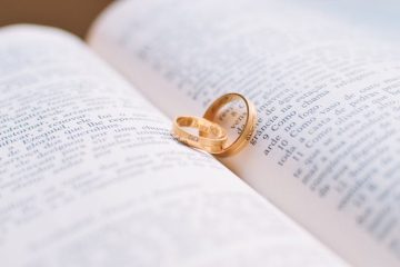 Two gold wedding rings resting on a book, symbolizing love and commitment.