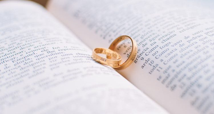 Two gold wedding rings resting on a book, symbolizing love and commitment.
