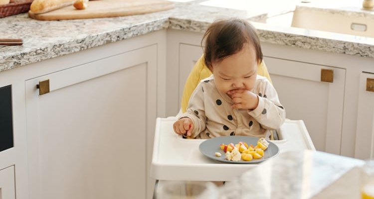 Baby seated, happily eating baby food.